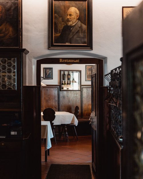 Blick durch einen Gang in ein traditionelles, gemütliches Restaurant mit Holzvertäfelung
