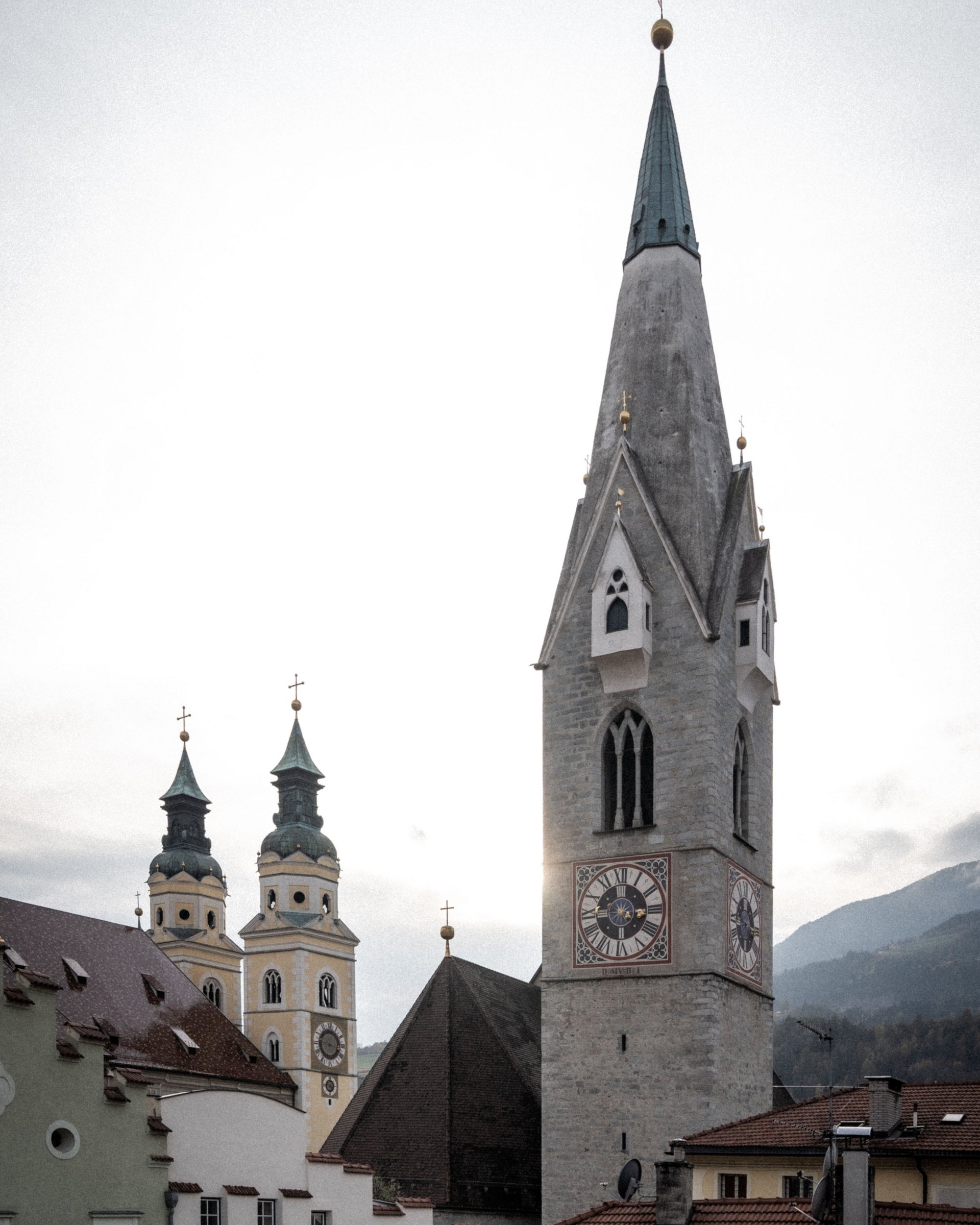Historic church towers with clock and traditional architecture under cloudy sky