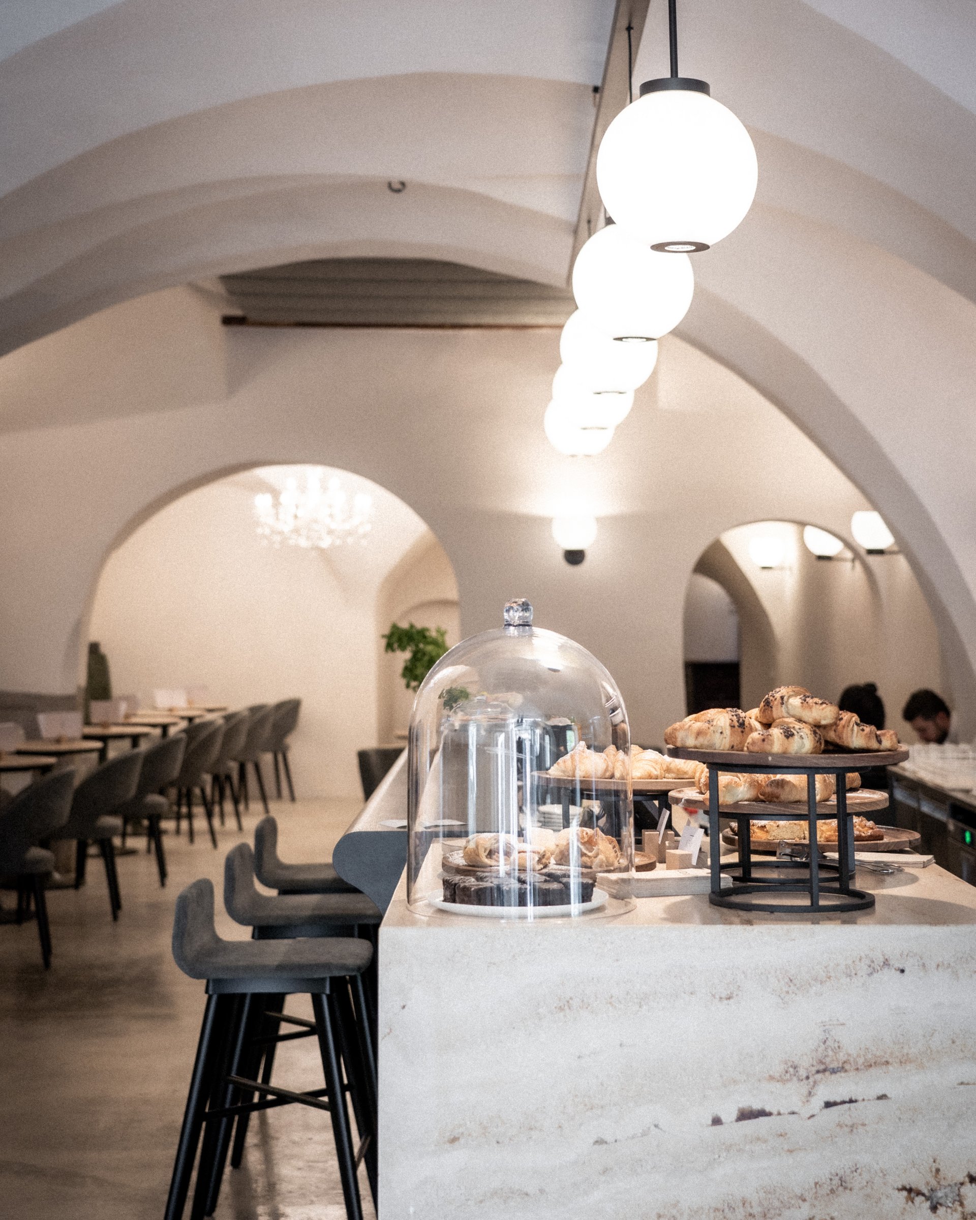 Gemütliches Café mit Croissants auf dem Tresen und modernen Innenbögen